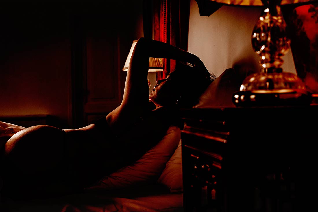 Boudoir fotoshoot in Groningen met sfeervol portret van een vrouw op een bed in warm licht.