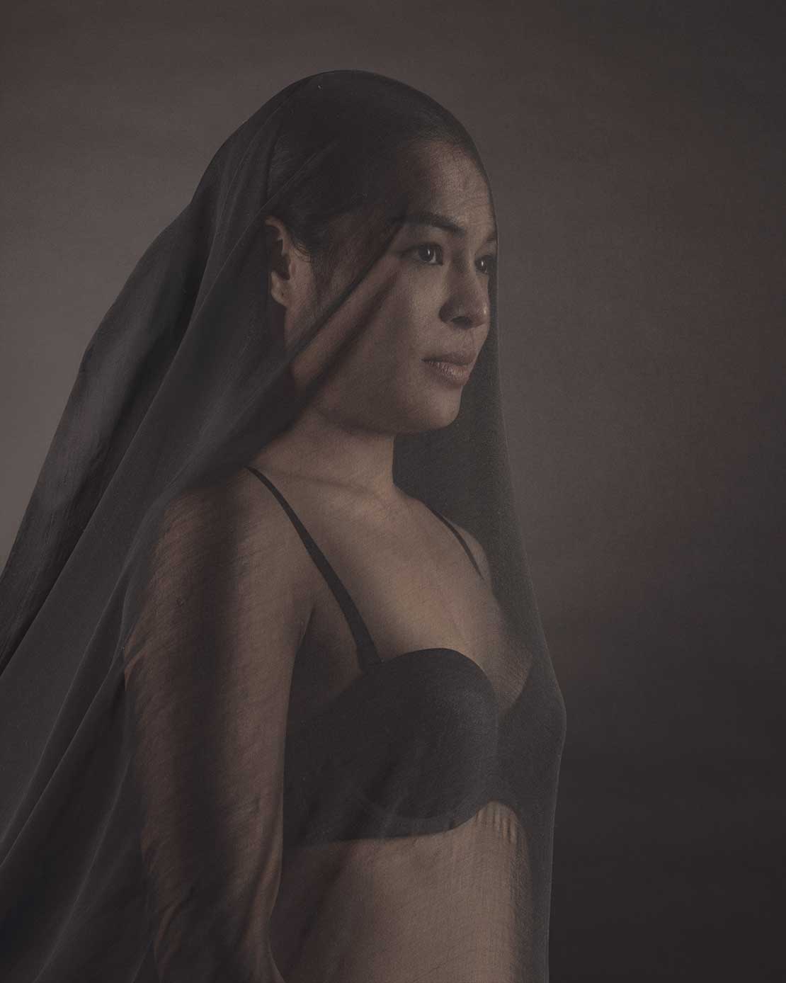 Boudoirfoto van een vrouw in lingerie met een transparante doek over haar hoofd.