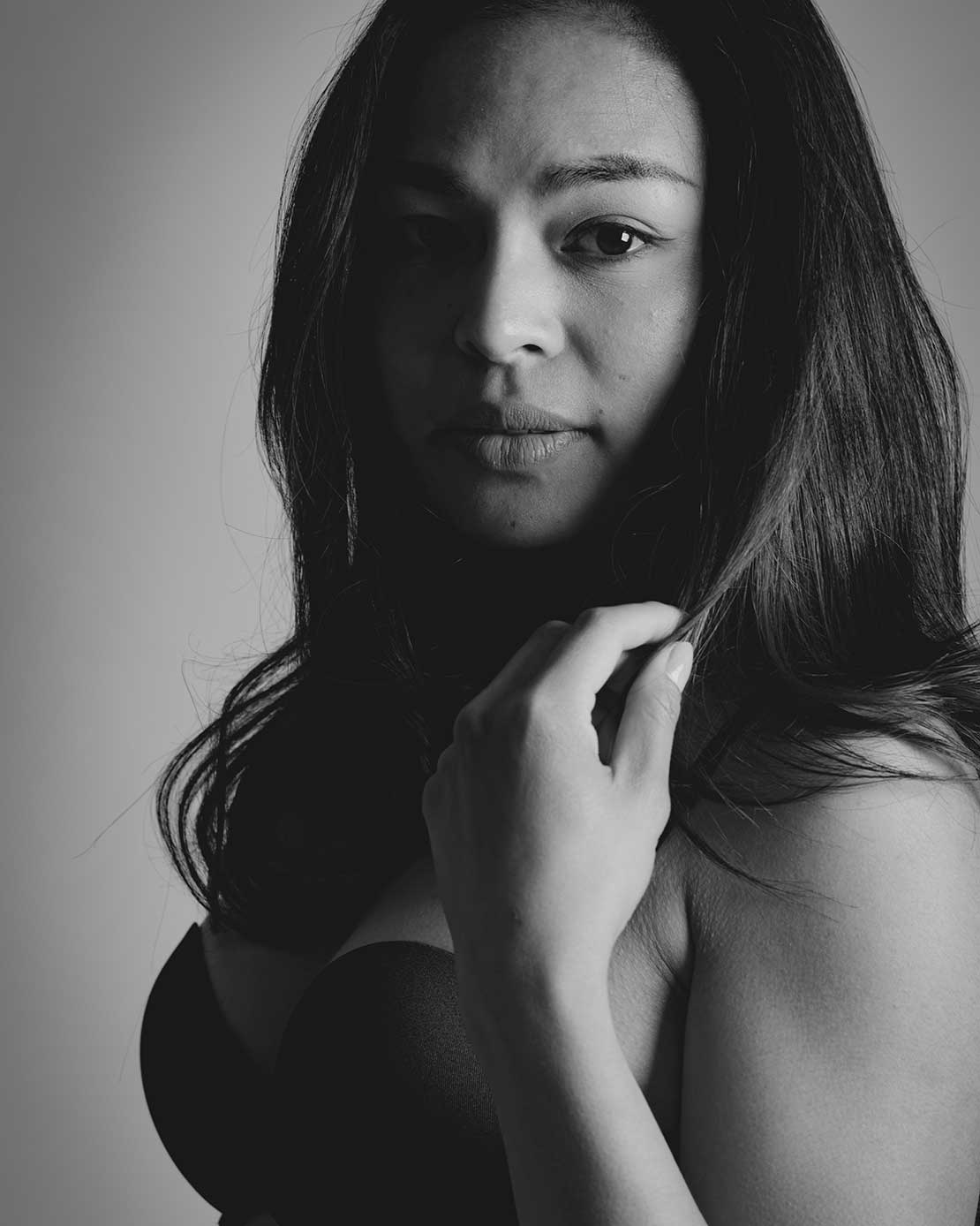 Zwart-wit boudoirportret van een vrouw in lingerie met zachte studioverlichting.
